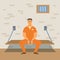 Prisoner in orange jumpsuit  is sitting in his cell