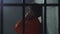Prisoner in orange uniform talks on phone in prison cell