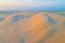 Pristine sand dunes glowing in orange sunrise.