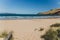 Pristine wild landscape at Clifton Beach in Tasmania, Australia with wavy blue ocean and golden sand next to a rugged coastline