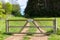 Private farm land fenced off by a large gate with a private keep out sign showing no access to the rural pathway