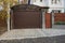 Private garage with a brown closed gate and part of a wooden fence