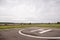 Private helipad after rain. An asphalt helipad against the backdrop of a green field and a cloudy evening sky