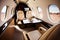 Private jet interior features plush leather seats, spacious cabin, large windows, high-end finishes, and a table.