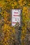 Private Property, No Trespassing sign hidden amount the yellow leaves of fall