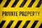 Private property warning sign stencil with yellow and black stripes painted over concrete wall cement texture background