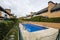 Private summer pool of a development of semi-detached single-family homes surrounded by hedges, grass and pots, a stone and grass