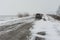 Private transport on a snowy highway struggle forward through snow-drift