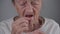 Problem of teeth in old age. Senior woman fitted denture in studio on gray background. Elderly female with gray hair and
