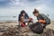 Problems of environmental pollution and oceans, a young couple in orange gloves cleans plastic and garbage in a black trash bag on