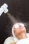 The procedure of steaming the skin of the face of a young woman before cleaning the skin,