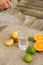 Proces of pouring cold water into a tall glass. Fresh citrus on table, orange, lemon and lime. Food concept