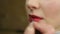 Process of applying red lipstick at makeup studio. Beautiful female lips closeup