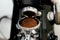 The process of automatic coffee grinding in a coffee grinder close-up. A handful of ground coffee in the holder