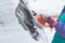 Process of cleaning a car from snow in the morning, girl removing snow from windscreen with a window scraper brush after snowstorm