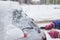 Process of cleaning a car from snow in the morning, girl removing snow from windscreen with a window scraper brush after snowstorm