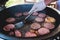 Process of cooking and grilling beef burgers on open-air street food festival, view of chef hands in gloves with variety of