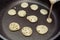 Process of cooking tiny pancake cereal - trendy quarantine food. Dough is poured into hot pan and mini pancakes are baked.