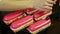 Process of decorating by big ripe raspberry pink glazed oval eclairs by confectioner