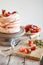 Process of decorating meringue cake with whipped cream and fresh strawberry