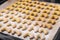 Process of dusting with icing sugar freshly home baked German Austrian traditional Christmas cookies vanilla crescents on tray