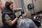 The process of dyeing hair in a barbershop, a professional hairdresser of a brown-haired woman works with a client
