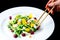 Process of eating with Chinese chopsticks delicious and appetizing salad with beetroot and fruit mango. Dish in a white plate