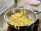 The process of frying french fries in a pan