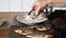 The process of frying river fish crucian carp in a black frying pan. An elderly woman is hand rolls the fish with flour before