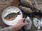 The process of frying river fish crucian carp in a black frying pan. An elderly woman is hand rolls flour on the fish