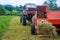 The process of harvesting hay for cattle, a tractor making bales in the field, old machinery