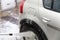 A process of indoor small silver colored car washing with stream of water from hose by hand