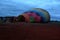 Process of inflation and preparation of hot air balloon at sunrise for flight in cloudy sky