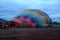 Process of inflation and preparation of hot air balloon at sunrise for flight in cloudy sky