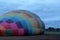 Process of inflation and preparation of hot air balloon at sunrise for flight in cloudy sky