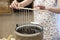 The process of making candles from natural wax . A woman holding ropes wicks over hot wax