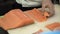 Process of making and cutting salmon for sushi rolls. Cook cutting up fish by knife on thin slices.