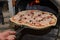 Process of making delicious pizza with ham, cheese and mushrooms in a pizzeria