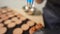 Process of making macaroon at home. Shot of hands of female pastry chef holding white macaron with ganache and squeezing