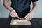 Process of making maki sushi. Cook chef hands preparing rolls with cheese, avocado and sesame seeds on wooden board