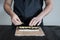 Process of making maki sushi. Cook chef hands preparing rolls with cheese, avocado and sesame seeds on wooden board