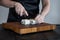 Process of making maki sushi. Cook chef hands preparing rolls with cheese, avocado and sesame seeds on wooden board