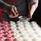 Process of making marshmallow. Close up hands of the chef with metal sieve sprinkling zephyr with Powdered sugar at pastry shop