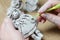 The process of making a souvenir doll made of clay. Female hands holding a toy made of clay.