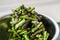 The process of mixing fresh chopped green asparagus with spices and salt in a shiny bowl