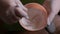 The process of mixing ingredients in a pink rubber cup. Close-up of the hands of a beautician or a lab technician in white gloves