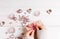 Process packing Christmas presents. White wooden table with pink decorations, balls, candles, stars, female hands