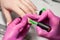 process of performing manicure in beauty salon. manicurist in pink gloves painting nails on hands of client with green shellac.