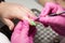 process of performing manicure in beauty salon. manicurist in pink gloves painting nails on hands of client with green shellac.