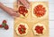Process preparation of galette from shortcrust pastry and fresh strawberries. Flat lay, four biscuits on baking paper. Female